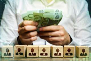 Foto: Figuren auf Würfeln und Hände mit Geldscheinen