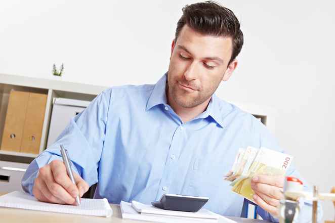 Foto: Mann mit Stift und Geldscheinen in den Händen